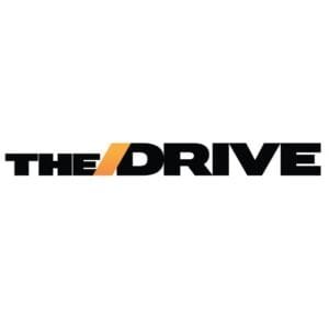 Logo of 'The Drive,' featuring the words 'THE' and 'DRIVE' in black, with a stylized orange line across the 'D' in 'DRIVE.' The design is bold and modern.