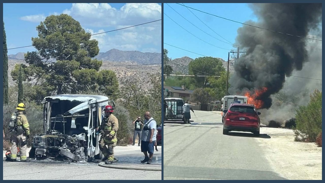 A burned mail truck sits on a roadside as firefighters stand nearby, with smoke rising behind a red car on the street.